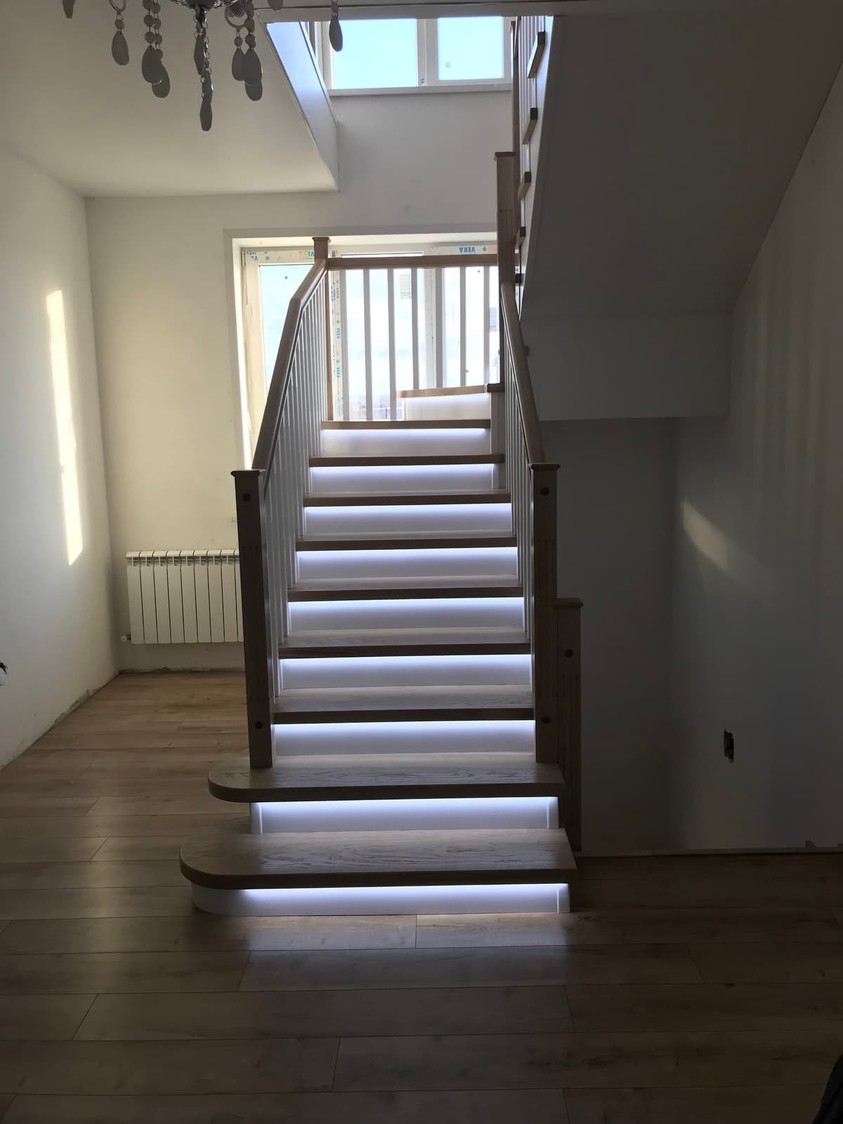 Элегантная лестница со шпонированными ступенями и включенной подсветкой в интерьере