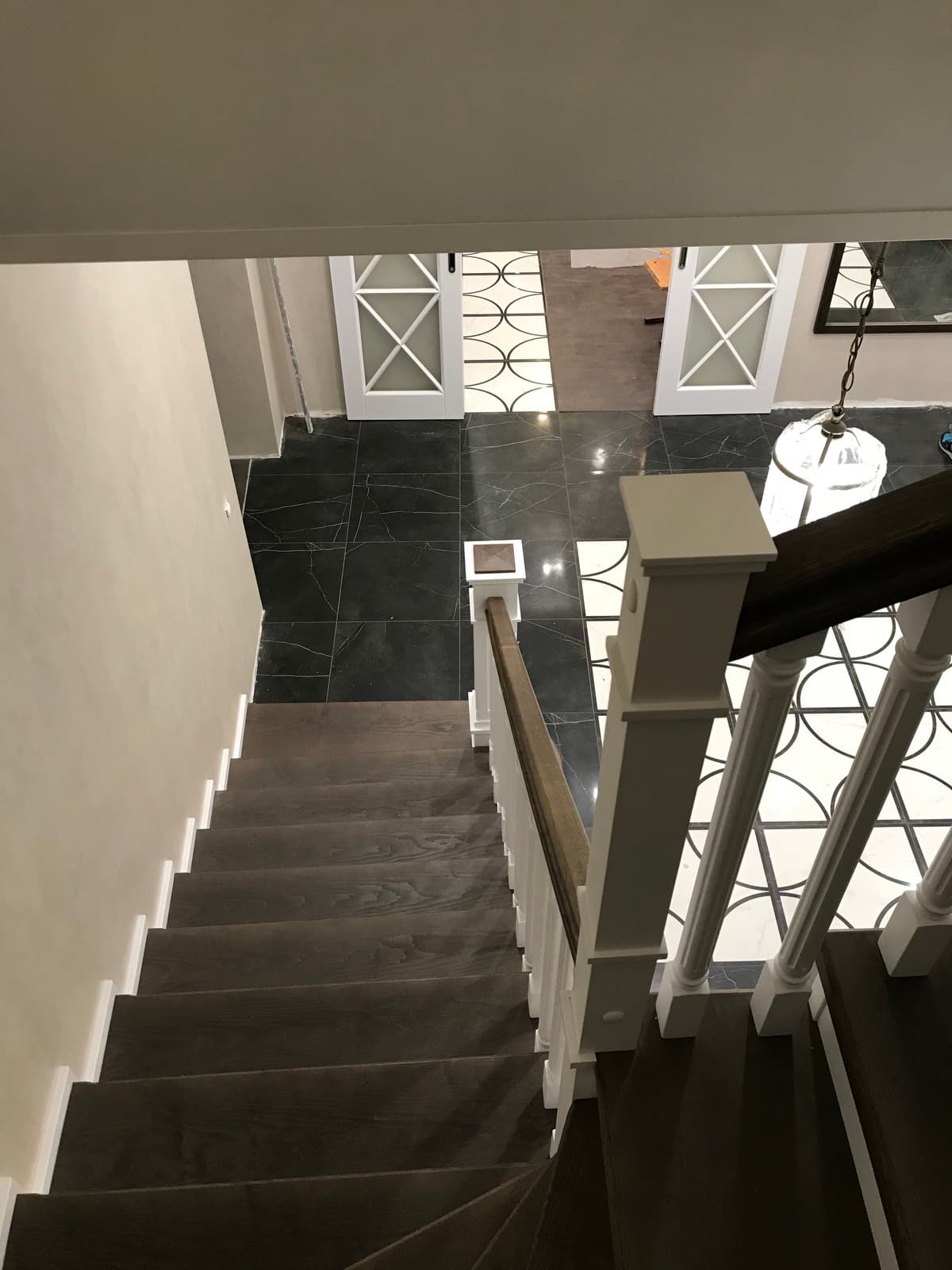 Двухцветная лестница на металлокаркасе закрытого типа в интерьере вид с лестницы