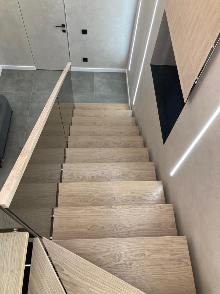 Лестница на металлическом монокосоуре со стекляным ограждением при спуске со второго этажа